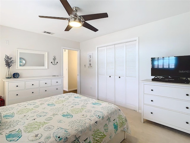 bedroom with a closet, visible vents, ceiling fan, and light carpet