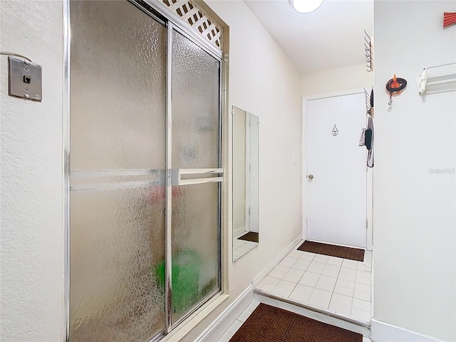 bathroom with an enclosed shower, tile patterned flooring, and baseboards