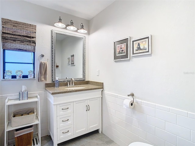 bathroom featuring wainscoting, vanity, and tile walls