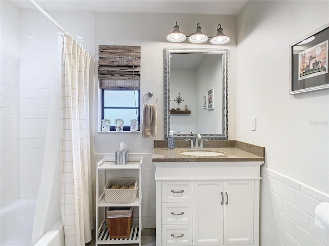 bathroom featuring wainscoting, shower / tub combo with curtain, tile walls, and vanity