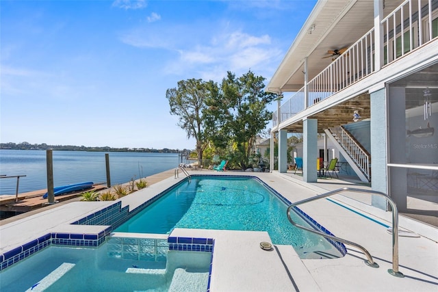 view of swimming pool with a water view, a pool with connected hot tub, stairway, and a patio