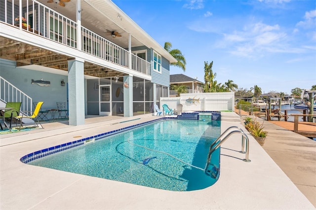 view of pool with a pool with connected hot tub, a sunroom, a patio area, fence, and ceiling fan