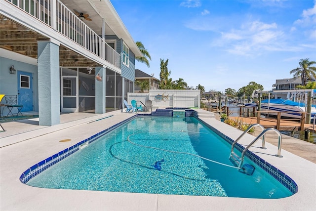 view of swimming pool with a boat dock, a pool with connected hot tub, fence, and a patio