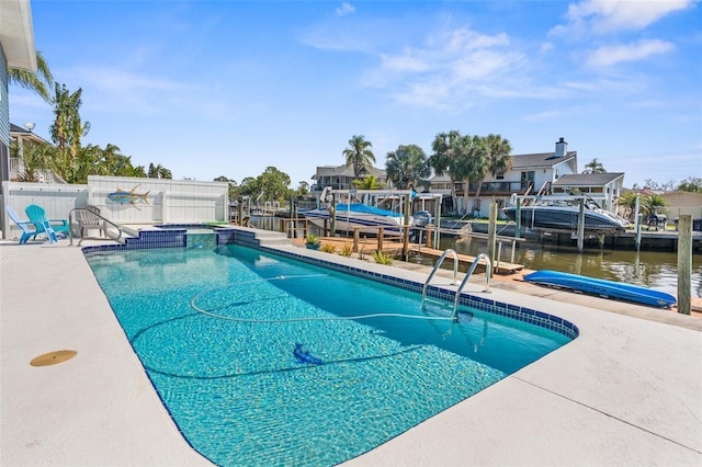 view of swimming pool with boat lift, a water view, a boat dock, fence, and a residential view