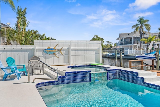 view of swimming pool featuring a water view, fence, and a pool with connected hot tub