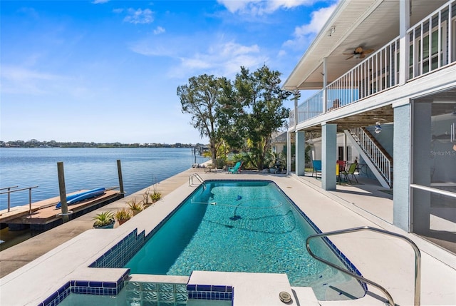 view of pool featuring a patio, a boat dock, a water view, and a pool with connected hot tub