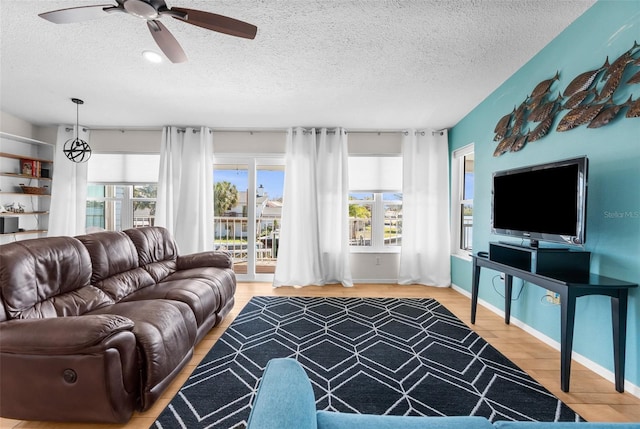 living room featuring a textured ceiling, wood finished floors, a wealth of natural light, and a ceiling fan