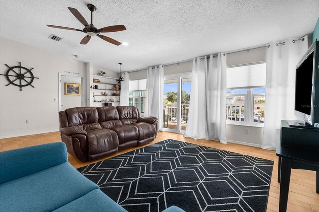 living room with lofted ceiling, a textured ceiling, wood finished floors, and visible vents