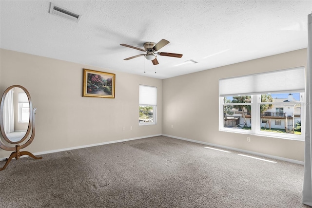 carpeted spare room with a textured ceiling, ceiling fan, visible vents, and baseboards