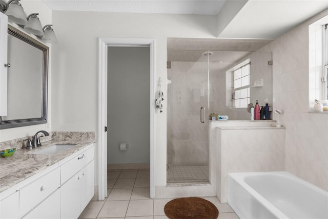 full bathroom featuring a stall shower, tile patterned flooring, a bath, and vanity