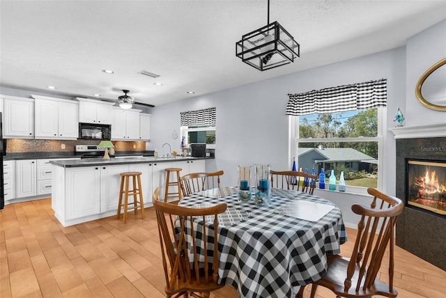 dining room featuring recessed lighting, visible vents, light wood-style flooring, a ceiling fan, and a high end fireplace