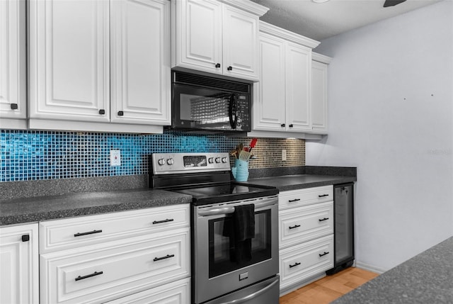 kitchen featuring dark countertops, decorative backsplash, white cabinetry, black microwave, and stainless steel electric range