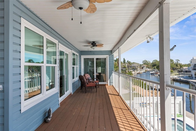 deck with a ceiling fan and a water view