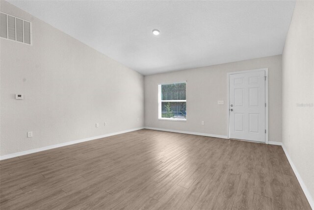 unfurnished room with wood finished floors, visible vents, and baseboards