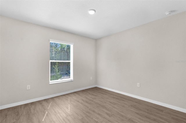 spare room featuring baseboards and wood finished floors
