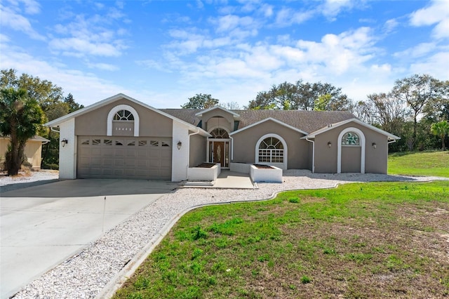 ranch-style house with a garage, brick siding, concrete driveway, stucco siding, and a front yard