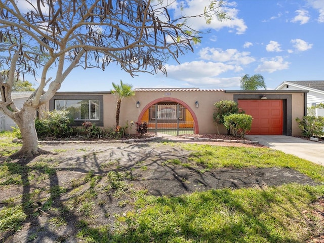 mediterranean / spanish house with a garage, driveway, fence, and stucco siding