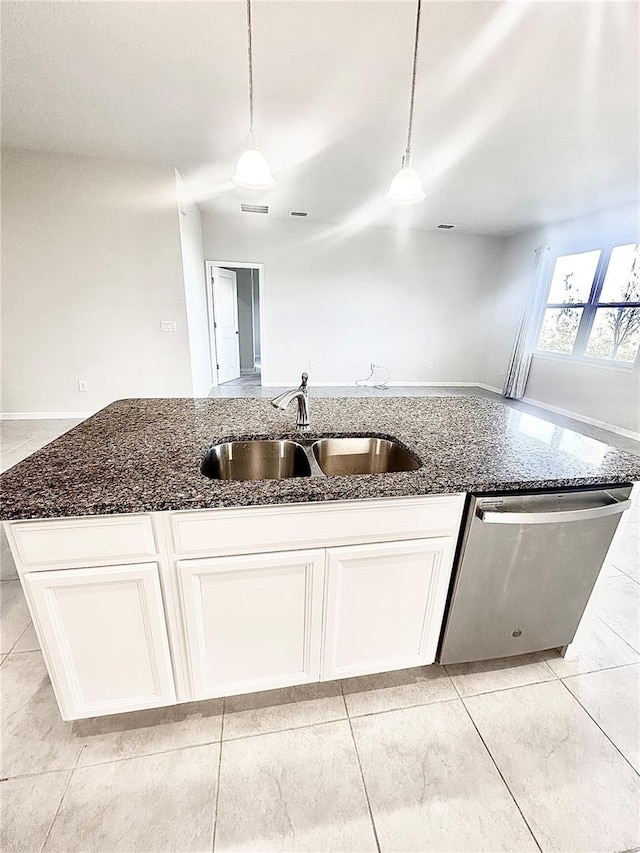 kitchen with a sink, white cabinetry, hanging light fixtures, stainless steel dishwasher, and dark stone countertops