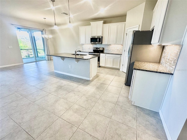 kitchen with tasteful backsplash, white cabinets, dark countertops, appliances with stainless steel finishes, and a sink