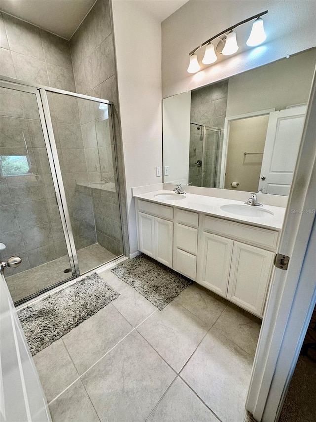 bathroom with double vanity, tile patterned flooring, a shower stall, and a sink