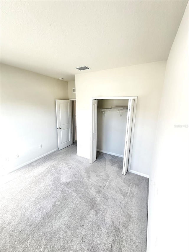 unfurnished bedroom with carpet floors, a closet, visible vents, and a textured ceiling