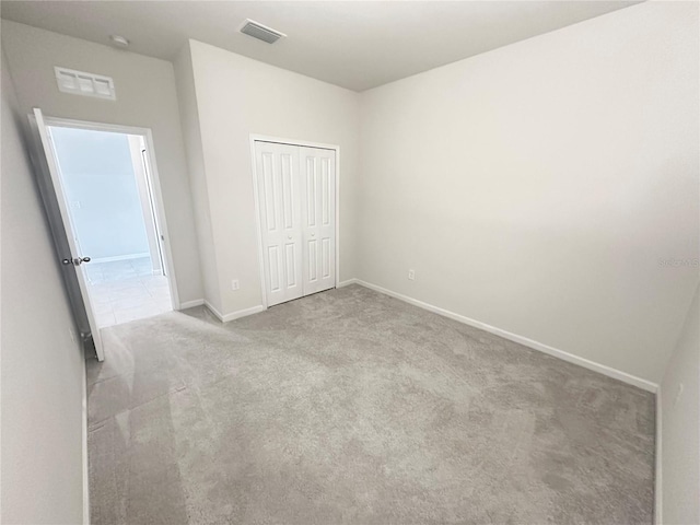 unfurnished bedroom featuring carpet floors, a closet, visible vents, and baseboards