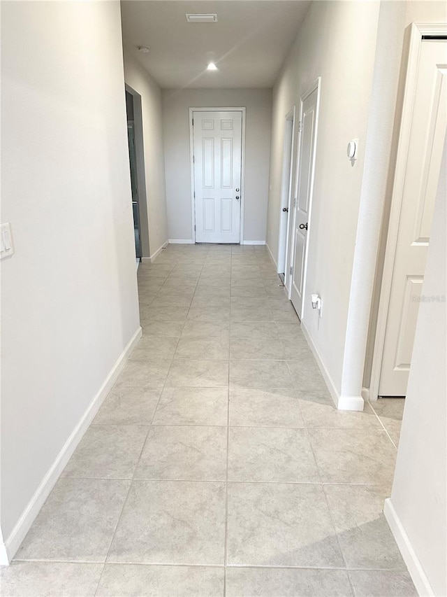 corridor featuring light tile patterned floors and baseboards