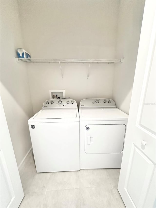 clothes washing area with laundry area, washer and clothes dryer, and light tile patterned floors