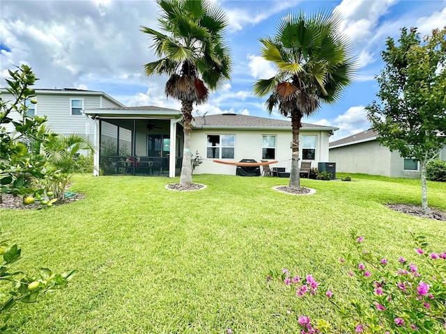 rear view of house featuring a lawn, a sunroom, and stucco siding