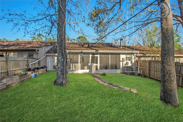 rear view of property with a sunroom, a fenced backyard, a chimney, and a lawn