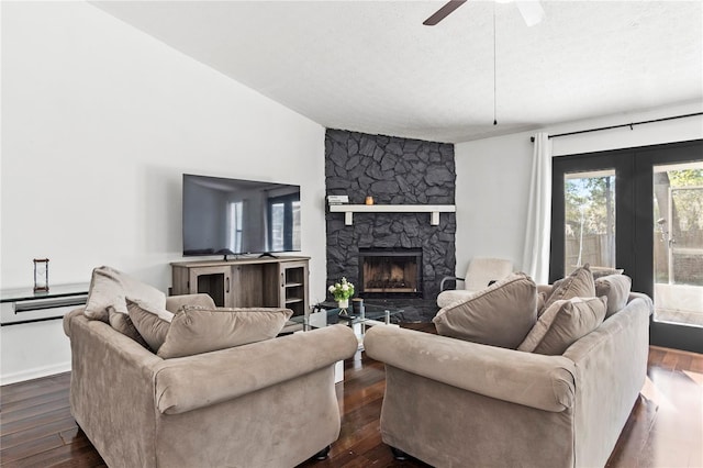 living area with a textured ceiling, a fireplace, a ceiling fan, and dark wood-style flooring