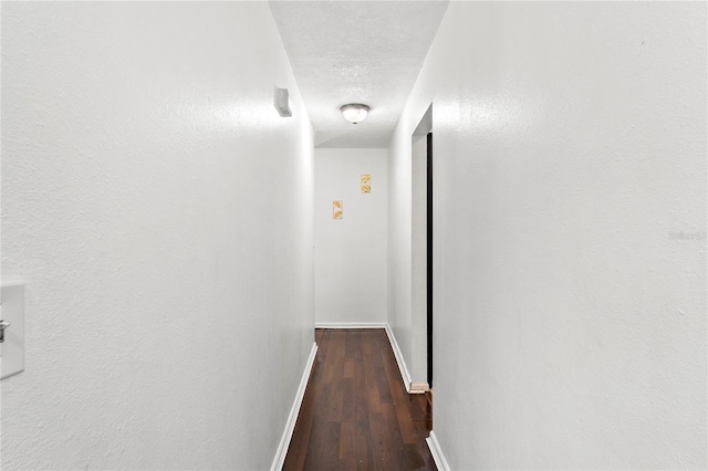 corridor featuring a textured ceiling, baseboards, and wood finished floors