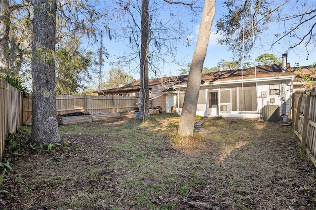 view of yard featuring a sunroom, a fenced backyard, and cooling unit