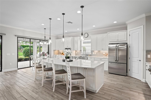 3130 Forsythia Dr, Odessa, FL 33556 - kitchen featuring high end refrigerator, backsplash, light wood-style flooring, white cabinetry, and a kitchen island