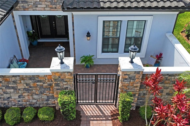 3130 Forsythia Dr, Odessa, FL 33556 - property entrance with stucco siding, a tile roof, stone siding, a gate, and covered porch