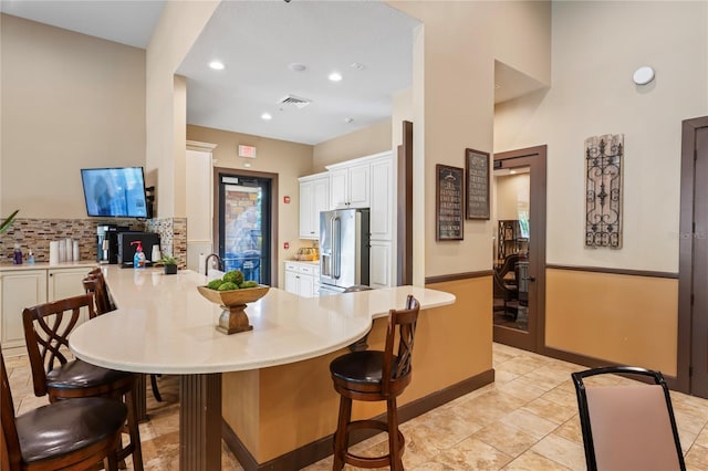3130 Forsythia Dr, Odessa, FL 33556 - kitchen with high end fridge, tasteful backsplash, a peninsula, white cabinetry, and a breakfast bar