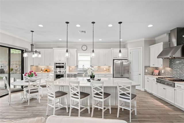 3130 Forsythia Dr, Odessa, FL 33556 - kitchen featuring stainless steel appliances, wall chimney exhaust hood, a center island, tasteful backsplash, and light countertops