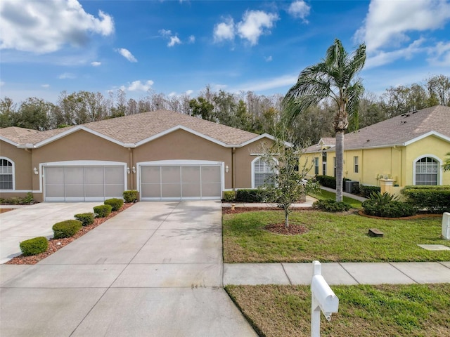 single story home featuring a shingled roof, concrete driveway, stucco siding, an attached garage, and a front yard