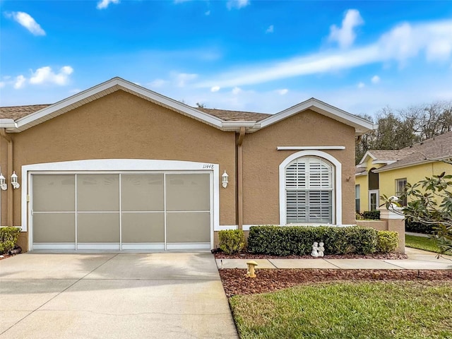 single story home with a garage, concrete driveway, and stucco siding