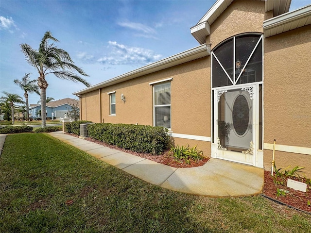 view of home's exterior with a yard, central AC unit, and stucco siding