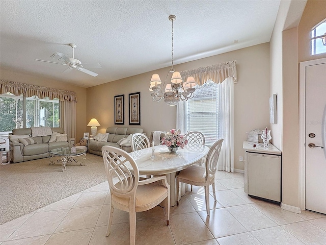 dining space with a textured ceiling, light tile patterned floors, ceiling fan with notable chandelier, and a healthy amount of sunlight