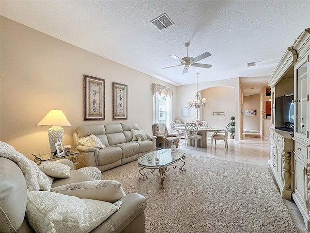 living area featuring a textured ceiling, light tile patterned floors, ceiling fan with notable chandelier, and visible vents