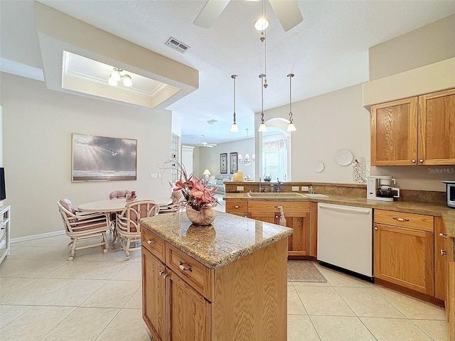 kitchen featuring white dishwasher, a peninsula, a sink, brown cabinetry, and a raised ceiling