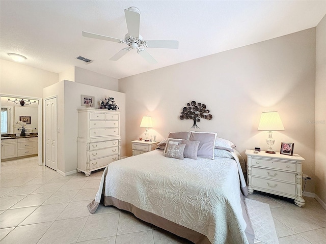 bedroom featuring light tile patterned floors, visible vents, a ceiling fan, ensuite bath, and baseboards