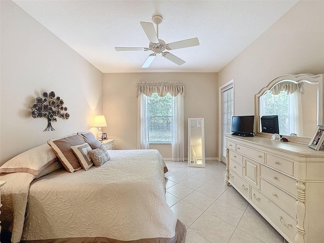 bedroom with a ceiling fan, light tile patterned flooring, a textured ceiling, and baseboards