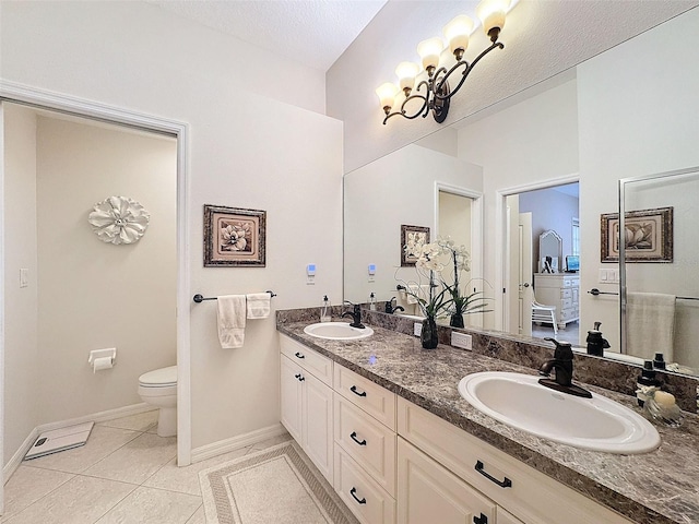 full bathroom with toilet, double vanity, a sink, and tile patterned floors