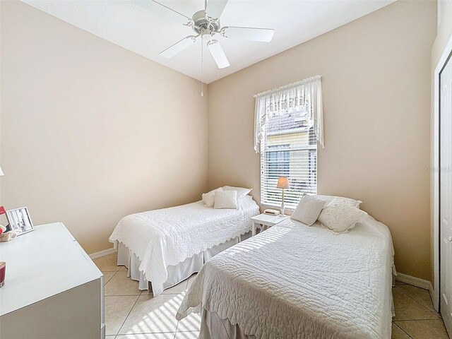 bedroom with light tile patterned floors, ceiling fan, and baseboards