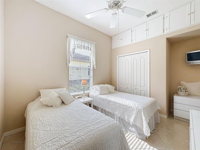 bedroom featuring light tile patterned floors, a closet, visible vents, a ceiling fan, and baseboards