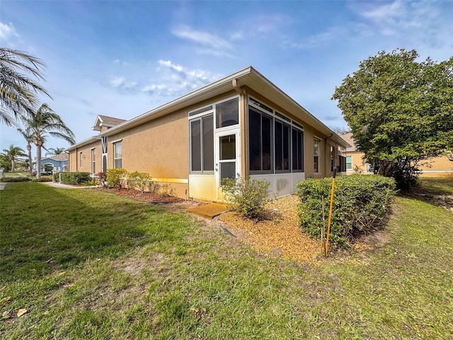 view of side of home featuring a sunroom, stucco siding, and a yard