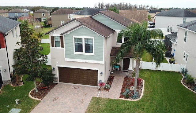 view of front facade featuring a residential view, fence, a front lawn, and decorative driveway